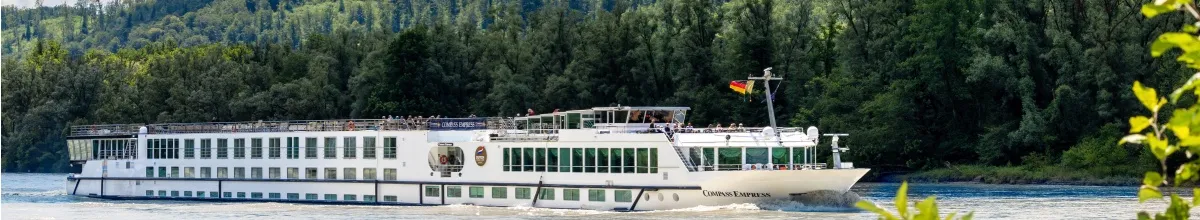 Seitenansicht der MS COMPASS EMPRESS. Im Hintergrund ein Waldabschnitt.