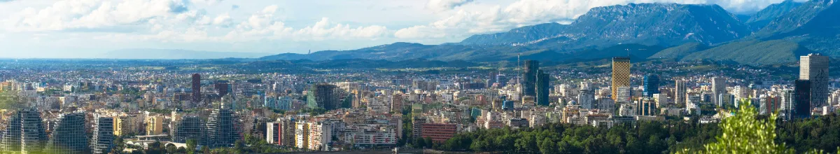 Panorama des urbanen Herzens von Tirana bei Tag mit einem angrenzenden Gebirge rechts.