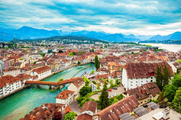 Vogelperspektive auf die Stadt Luzern, direkt am Fluss Reuss gelegen bei Tag, dominiert durch ihre rot-geschindelten Dachpfannen.