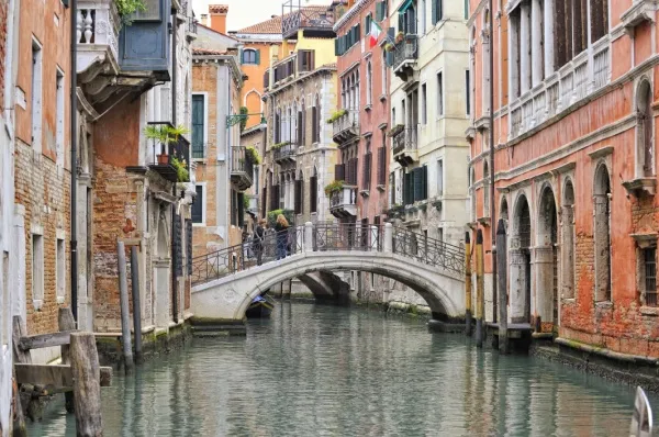 Fluss zwischen den bunten Häusern von Venedig, in der Mitte eine kleine Brücke.