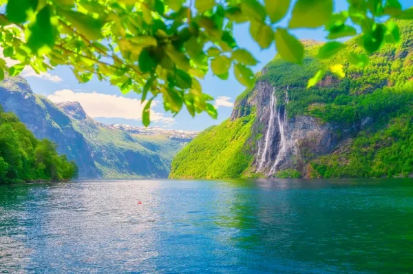Die Wasserfälle "Sieben Schwestern" an steilen Felsklippen am Fjord inmitten grüner Natur.