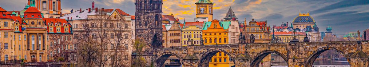 Panorama einer historischen europäischen Stadt mit alter Steinbrücke und prächtigen Bauten am Flussufer, die zum Entdecken auf einer historischen Kreuzfahrt einlädt.