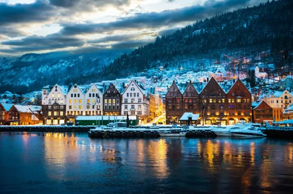 Nordeuropas Küsten: Wo Mythen, Sagen und eine raue, herzliche Kultur zu Hause sind Verschneite historische Hafenansicht von Bryggen in Bergen, Norwegen, bei Dämmerung, die die raue Schönheit und Kultur Nordeuropas widerspiegelt.