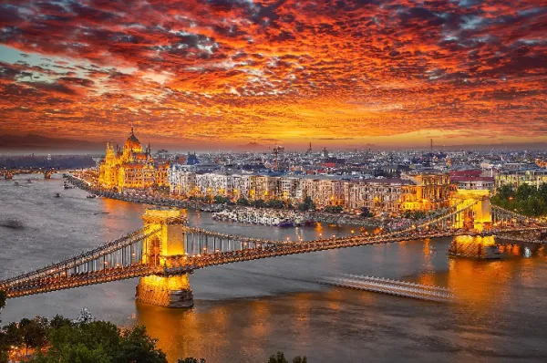 Die Donau: Römischer Limes, osmanisches Erbe und Schauplatz europäischer Geschichte Budapest an der Donau bei Sonnenuntergang mit beleuchteter Kettenbrücke und Parlamentsgebäude, Symbol für die reiche Geschichte und kulturelle Bedeutung des Flusses als römischer Limes und osmanischer Einflussbereich.