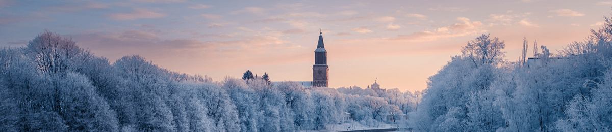 Der vereiste Fluss Aurajoki in der schneebedeckten Winterlandschaft von Turku. Im Hintergrund ist der Kirchturm der Kathedrale von Turku zu sehen.
