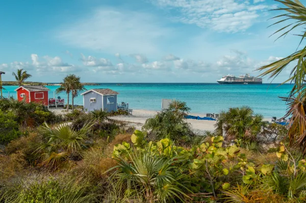 Ein Strand auf Half Moon Cay Ein Strand der Kreuzfahrtinsel Half Moon Cay mit einem Kreuzfahrtschiff im Hintergrund bei Tag.