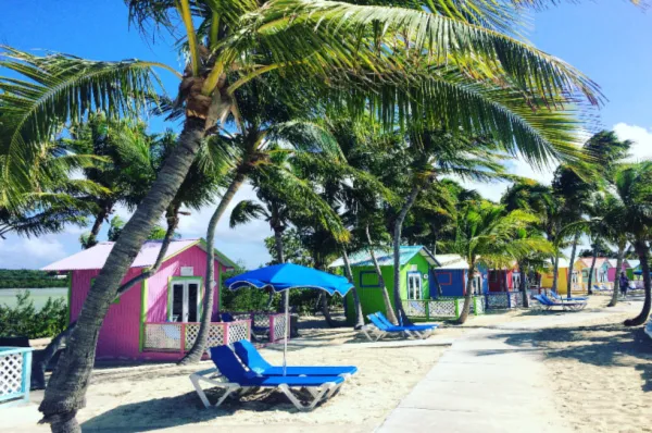 Die Kulisse von Princess Cays Bunte Cabanas, Liegen und Palmen an einem angelegten Weg auf Princess Cays bei Tag.