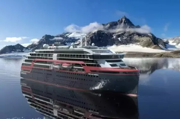 Die MS Fridtjof Nansen auf dem Wasser vor schneebedeckten Bergen.