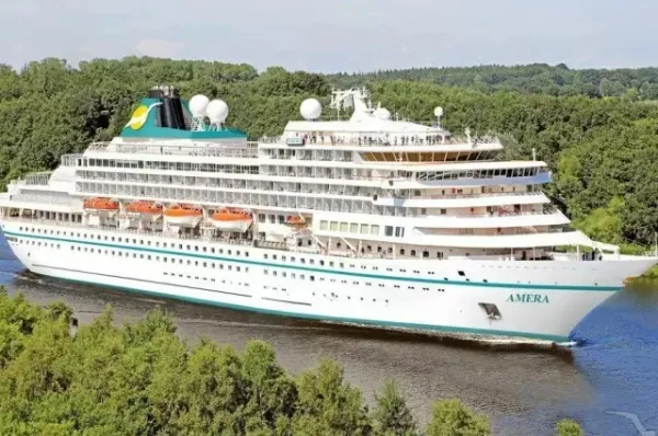 Die MS Amera schippert über das Wasser umgeben von grüner Natur.