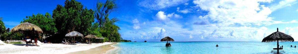 Strand von Fakarava am türkisblauen Meer mit Sonnenschirmen.