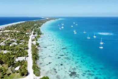Fakarava von oben Die Küste von Fakarava inmitten des türkisblauen Meeres mit kleinen weißen Segelbooten auf dem Wasser.