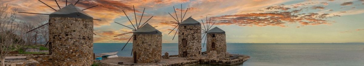 Eine Reihe Windmühlen auf Chios, in alter Steinoptik bei Sonnenuntergang.