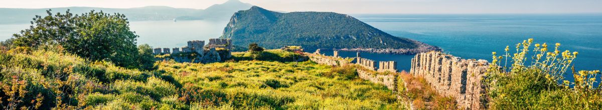 Ausblick über die Naturszenerie von Pylos mit Bergen, Meer und alten Ruinen bei Tag.