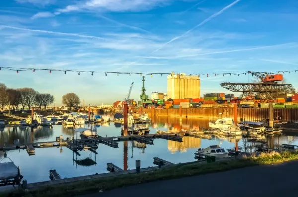 Der Hafen von Gernsheim mit einigen kleinen Booten vor Anker und Industrie im Hintergrund bei Sonnenuntergang.
