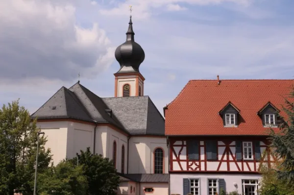 Eine Kirche und ein Fachwerkhaus in Gernsheim bei Tag.