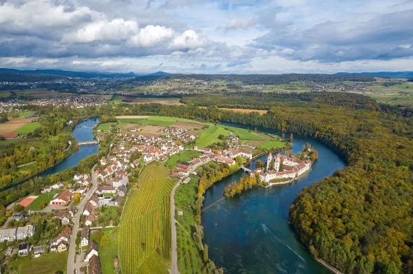 Totale von Mettlach Vogelperspektive der Stadt Mettlach bei Tag mit der angrenzenden Saar und den Gebäuden der Stadt, alles umgeben von dichten, grünen Wäldern.