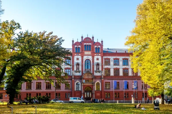Die Universität von Rostock Rostocks rot-geziegeltes Universitätsgebäude am Tag mit einer Grünfläche im Vordergrund.