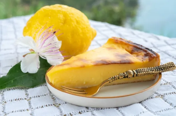 Eine Zitrone und ein Stück Zitronenkuchen liegen auf einem schön gedeckten Tisch.