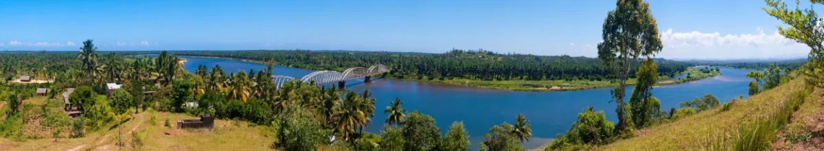 Fluss auf Madagaskar mit Brücke umgeben von grüner Naturlandschaft.