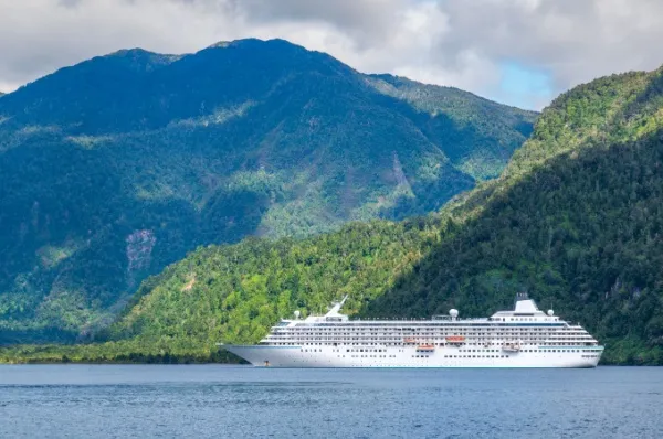 Puerto Chacabuco Kreuzfahrtschiff auf dem Wasser vor grüner Berglandschaft.