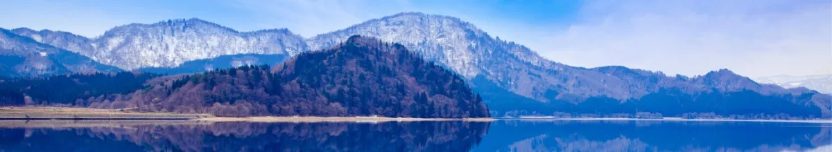 Eine imposante Bergkulisse bei Akita, angrenzend ans Wasser bei Tag.