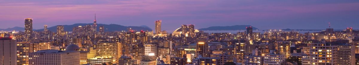 Die nächtliche Skyline von Fukuoka mit beleuchteten Gebäuden, die sich bis zum Horizont ausbreiten.