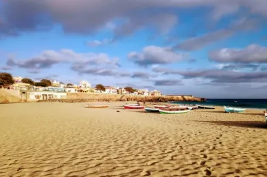 Sandstrand mit kleinen, bunten Fischerbooten unter blauem Himmel.
