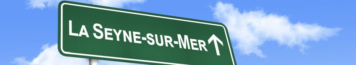 Ein grünes Ortsschild auf dem "La Seyne-sur-Mer" steht vor einem blauen Himmel.