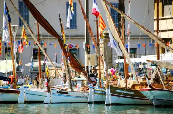 Eine Reihe von Booten im Hafen von La Seyne-sur-Mer mit verschiedensten bunten Flaggen bei Tag.