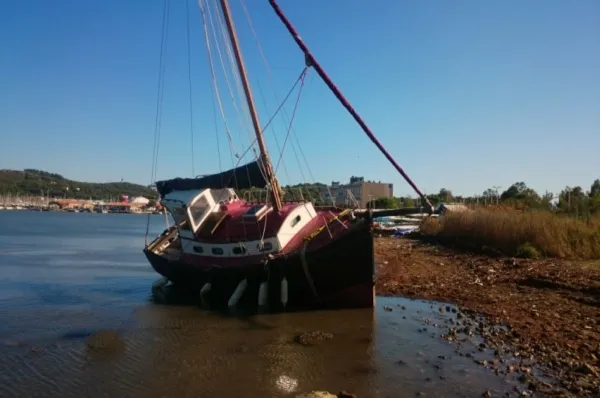 Ein alter Fischkutter, gestrandet in seichtem Wasser an der Promenade bei La Seyne-sur-Mer am Tag.