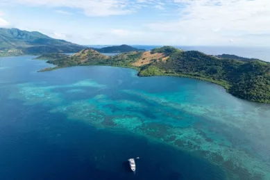 Naturparadies Maumere umgeben von türkisfarbenem Meer und Korallenriffen, auf dem Meer ruht ein kleines Boot.