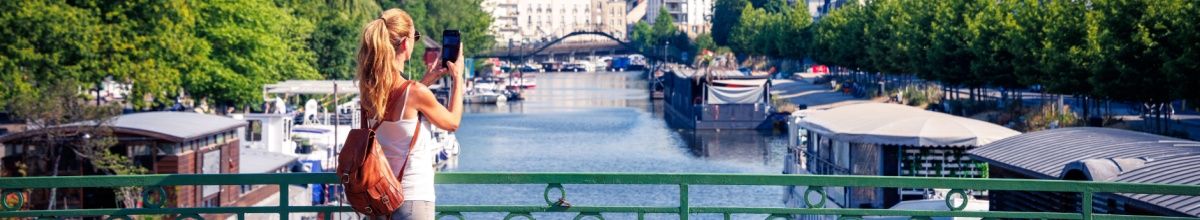 Eine Frau auf einer Brücke in Nantes, die über die Loire schaut mit der Stadt im Hintergrund bei Tag.