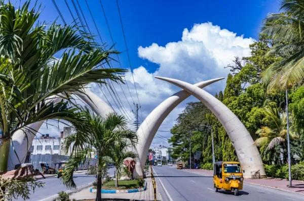 Eine breite Straße in Mombasa bei Tag mit gekreuzten Elefantenstoßzähnen.