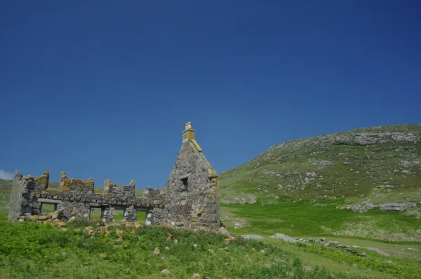 Ruine Die Ruine eines Hauses steht auf einer grünen Wiese auf der Insel Mingulay.