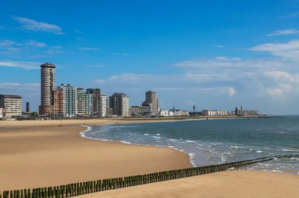 Stadtstrand von Vlissingen mit Hochhäusern im Hintergrund an der blauen Nordsee unter blauem Himmel.