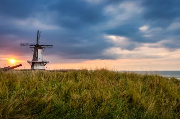 Windmühle in Dünen bei Sonnenuntergang.