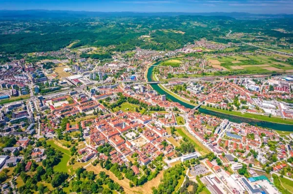Eine Totale von Karlstadt aus der Vogelperspektive mit dem Stadtgebiet, was sich an Main und Natur einbettet, bei Tag.
