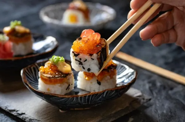 Sushi liegt angerichtet auf einem schwarzen Teller.