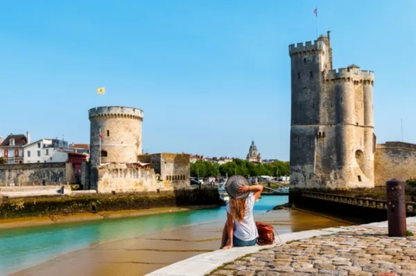 Eine Reisende in Royan, die auf zwei alte Bollwerke schaut, die eine Mündung umsäumen bei Tag.