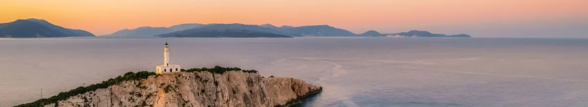 Ein pittoresker Sonnenuntergang über Lefkada mit einem Leuchtturm auf einem einsamen Felsen, im Hintergrund das Meer.