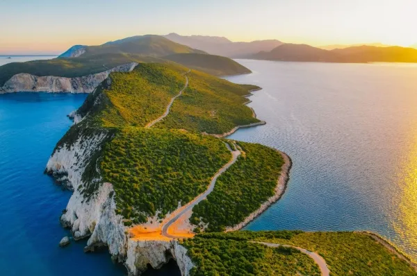 Die Landschaft von Lefkada Die Naturkulisse der Insel Lefkada bei einem beeindruckenden Sonnenuntergang, geprägt durch grüne Hügel und Meer.