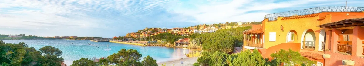 Panorama der Küste bei Porto Cervo am tag mit vielen bunten Häusern und dem angrenzendem, türkisen Meer.