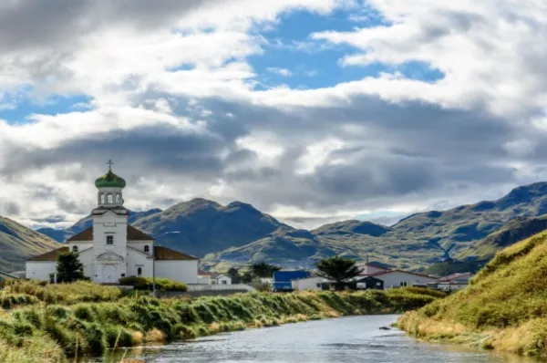 Eine Kirche in Dutch Harbor bei Tag, gelegen am Wasser mit den Dächern der Stadt im Hintergrund.