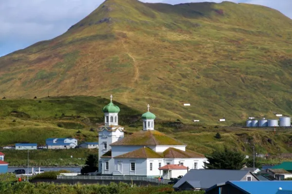 Die orthodoxe Kirche Holy Ascension bei Tag, im Hintergrund ein großer, grüner Hügel.