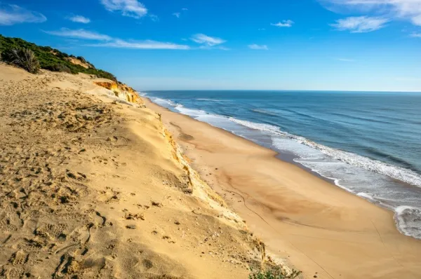 Sandstrand am türkisfarbenen Mittelmeer unter blauem Himmel.