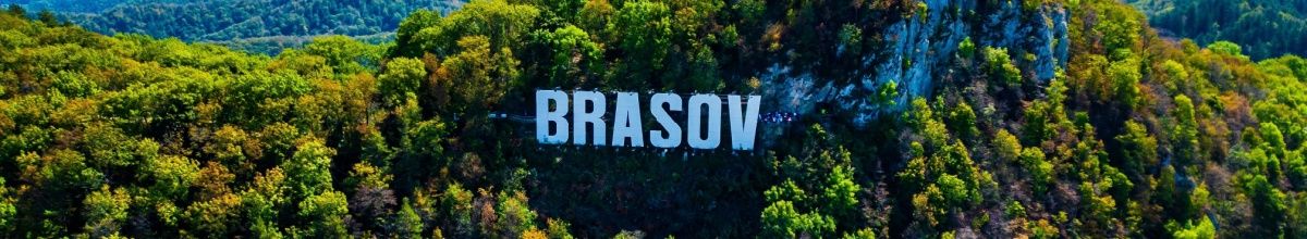 Ein riesiges Schild mit der Aufschrift "Brasov" bei der Stadt an der Flanke eines grünbewachsenen Berges bei Tag.