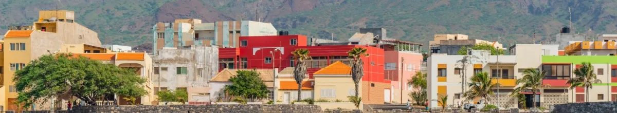 Häuser an den Meeresklippen auf Porto Santo bei Tag mit einem Bergmassiv im Hintergrund.