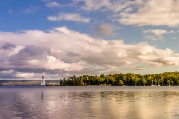 Eine Landzunge, die in die Gewässer um Baddeck ragt mit einem Leuchtturm an ihrer Spitze und einem Wald dahinter.