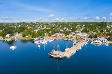 Der Hafen von Baddeck am Tag mit einem langen Pier, einigen Booten und den Häusern des Ortes.