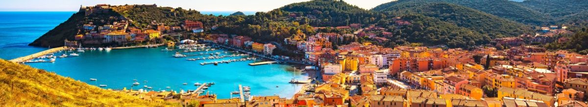 Panoramablick auf die Bucht und den Hafen von Porto Ercole mit bunten Häuserfassaden.